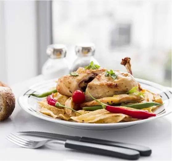 Gebratenes Hähnchen auf knusprigen Kartoffelspalten, serviert mit Chili, grünen Bohnen und frischen Kräutern.
